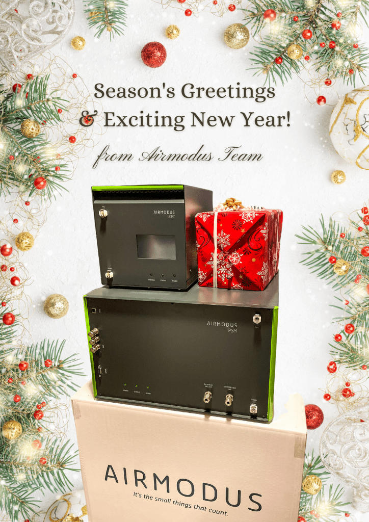 Picture of Airmodus aerosol instruments and a Christmas gift, on an Airmodus box, surrounded by Christmas decorations, and text Season's Greetings & Exciting New Year from Airmodus Team